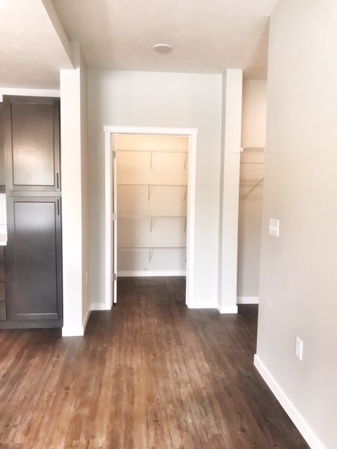 A kitchen with a refrigerator and wooden floors.