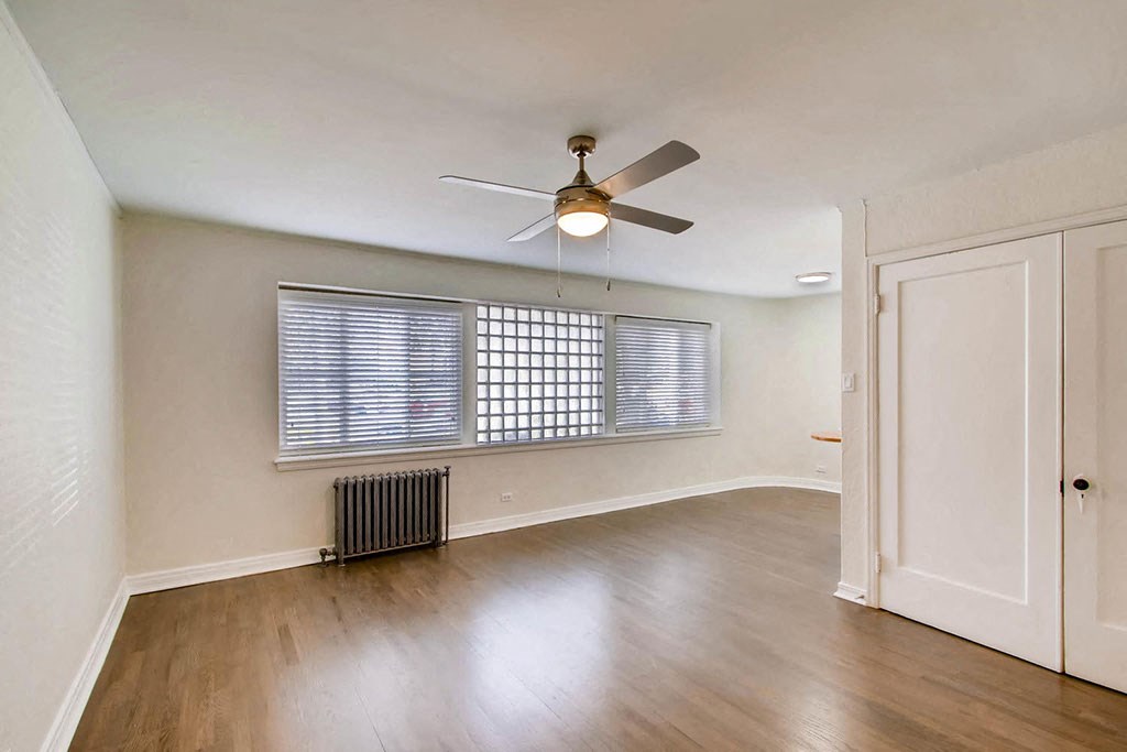 an empty living room with a ceiling fan and a window
