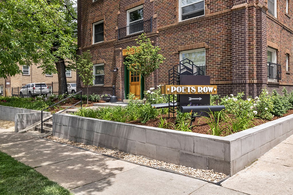 a garden with a sign in front of a brick building