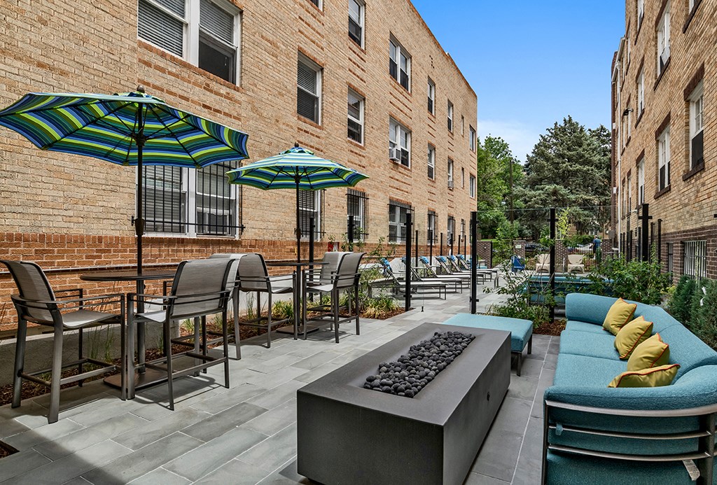 a patio with tables and chairs and umbrellas in front of a brick building