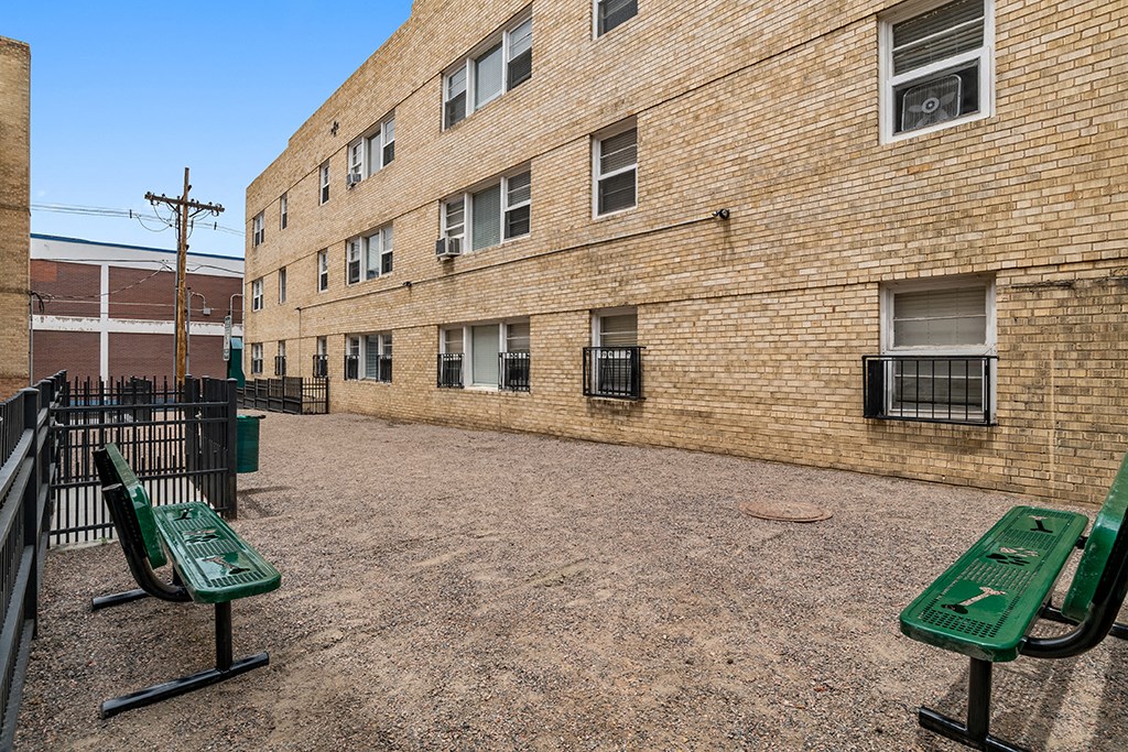 a green park bench in front of a brick building