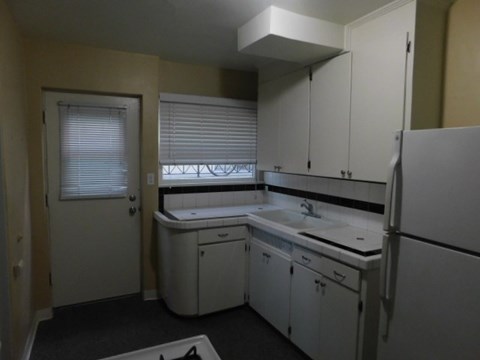 a kitchen with white cabinets and a refrigerator and a sink