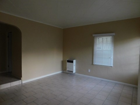 an empty living room with a heater in the corner