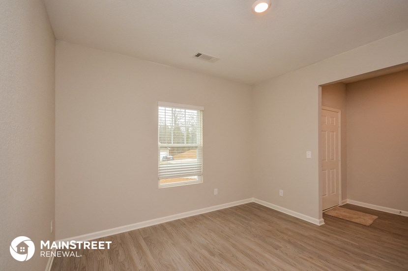 the upstairs bedroom with hardwood flooring and a window
