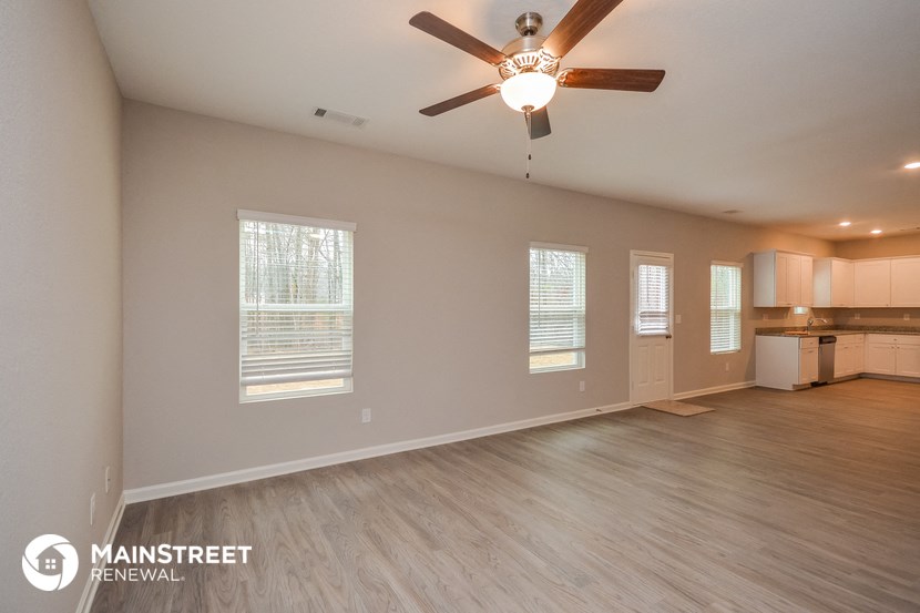 the living room and kitchen of an empty house with a ceiling fan