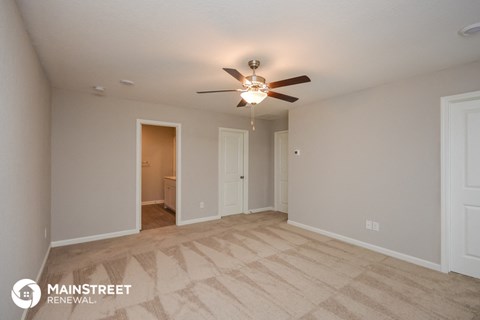 the spacious living room with carpet and ceiling fan