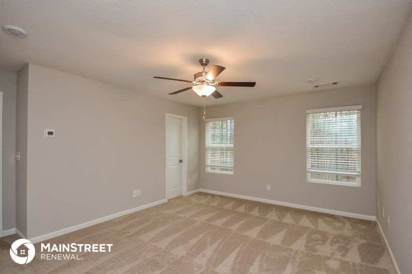 the spacious living room with carpet and ceiling fan
