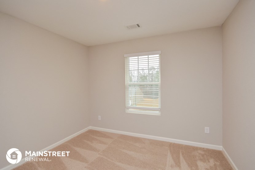 the upstairs bedroom has a large window and beige walls