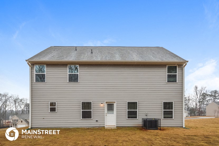 the front of a white house with a gray roof and a blue sky