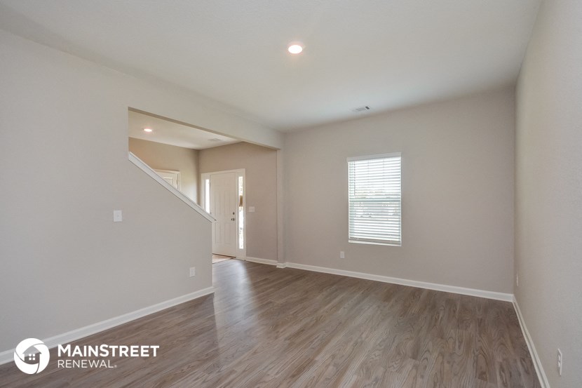 the spacious living room with hardwood flooring and a staircase