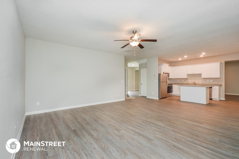 a living room with a ceiling fan and a kitchen