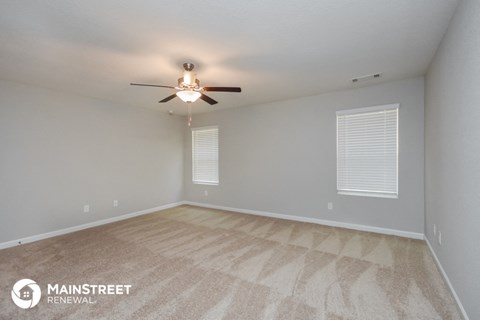 the spacious living room with carpet and ceiling fan