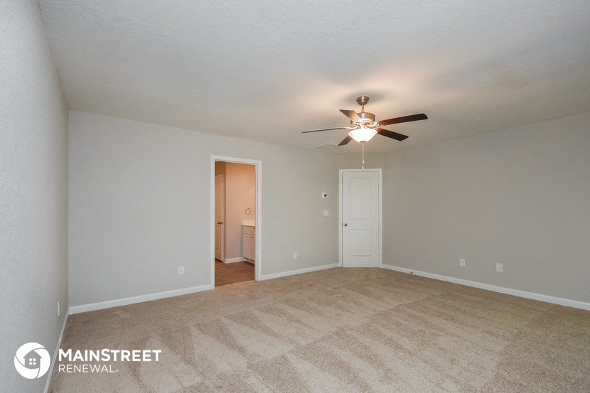 the spacious living room with carpeting and a ceiling fan
