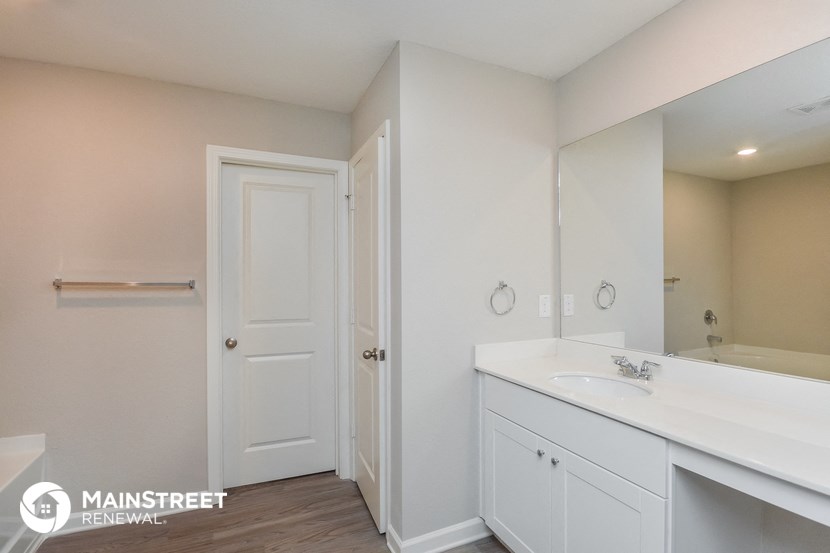 a bathroom with white cabinets and a sink and a mirror