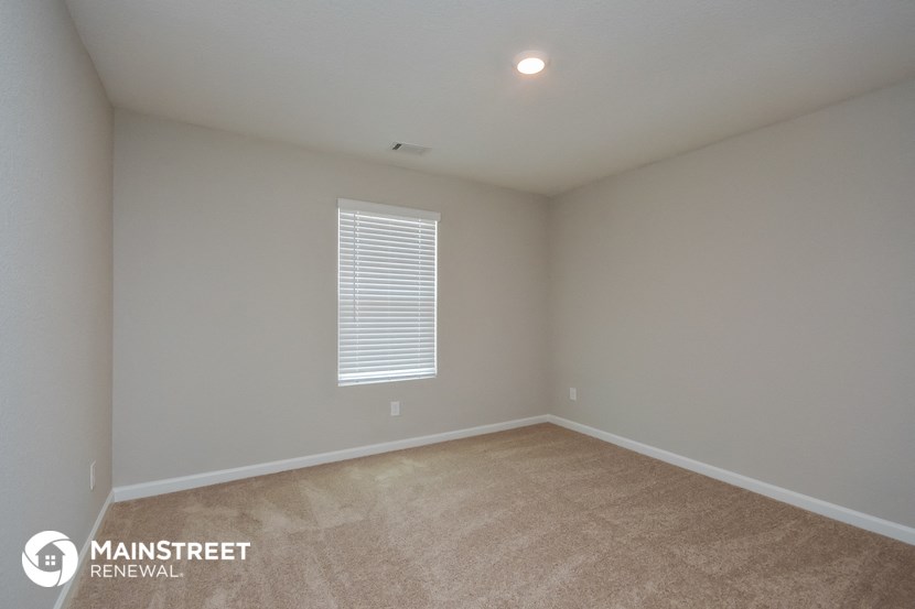 the spacious living room with carpeting and a window