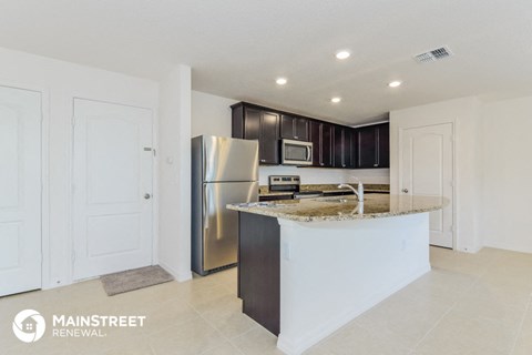 a kitchen with a granite counter top and a stainless steel refrigerator