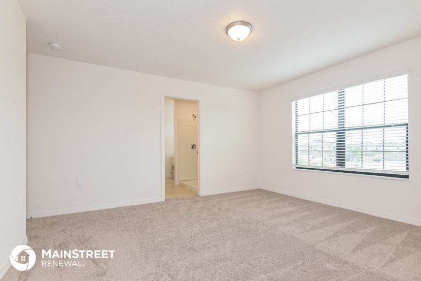 a spacious living room with a large window and carpeting