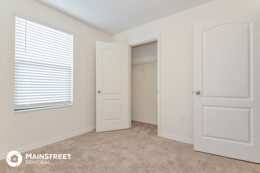 a bedroom with a closet and a window and a door to a closet