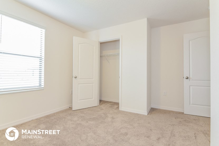 a bedroom with a closet and a window and a door to a closet