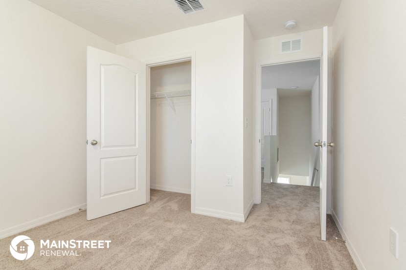 a bedroom with two closets and a carpeted floor and a hallway with doors