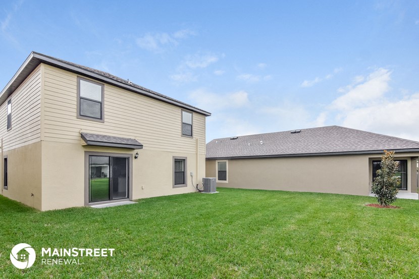 the exterior of a house with a yard and another house behind it