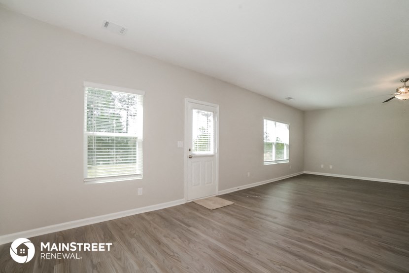 the spacious living room with wood flooring and windows