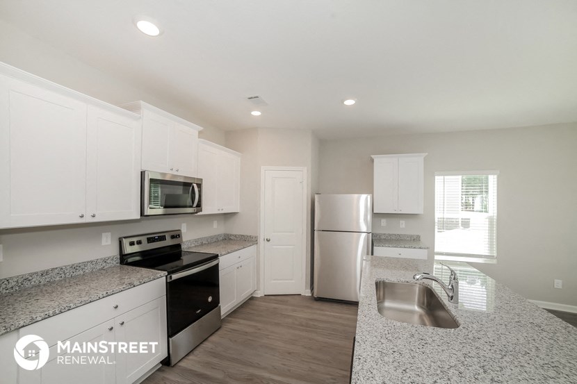 the kitchen has granite counter tops and white cabinets and stainless steel appliances