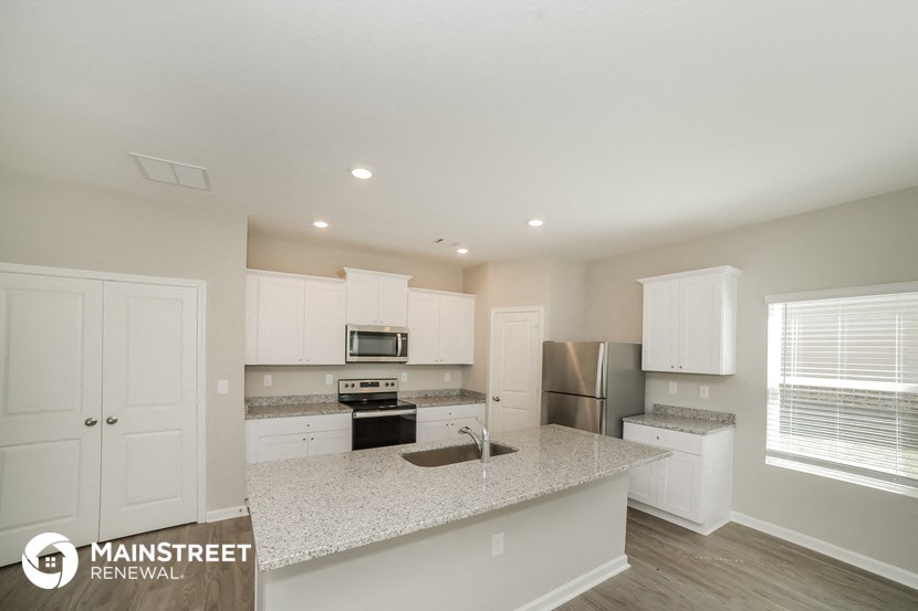 the kitchen of an apartment with white cabinets and a granite counter top