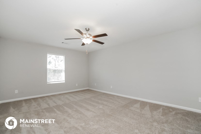 an empty room with a ceiling fan and a window