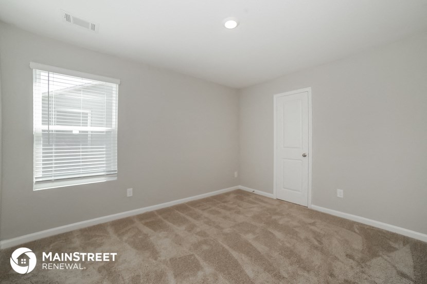the upstairs bedroom with carpeted flooring and a white door