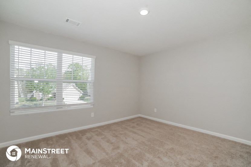 the spacious living room with a large window and beige carpet
