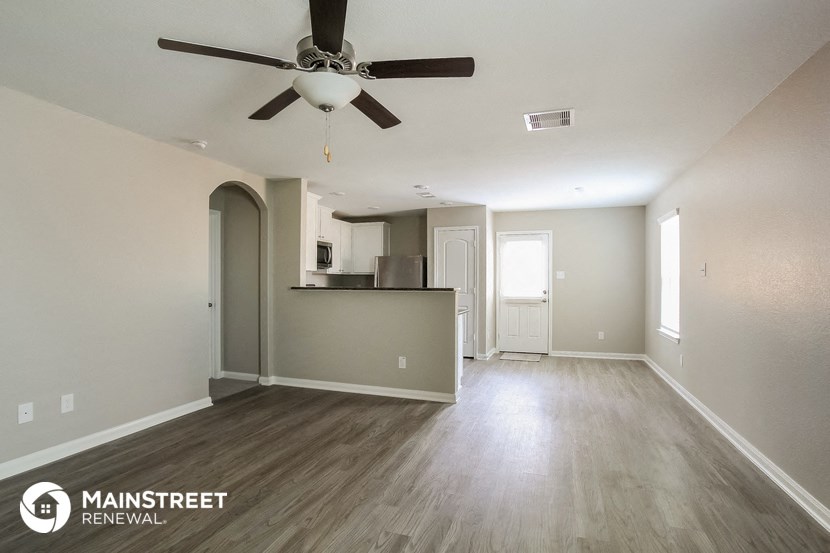 an empty living room and kitchen with a ceiling fan