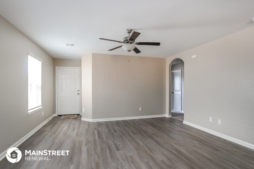 the spacious living room with ceiling fan and wood flooring