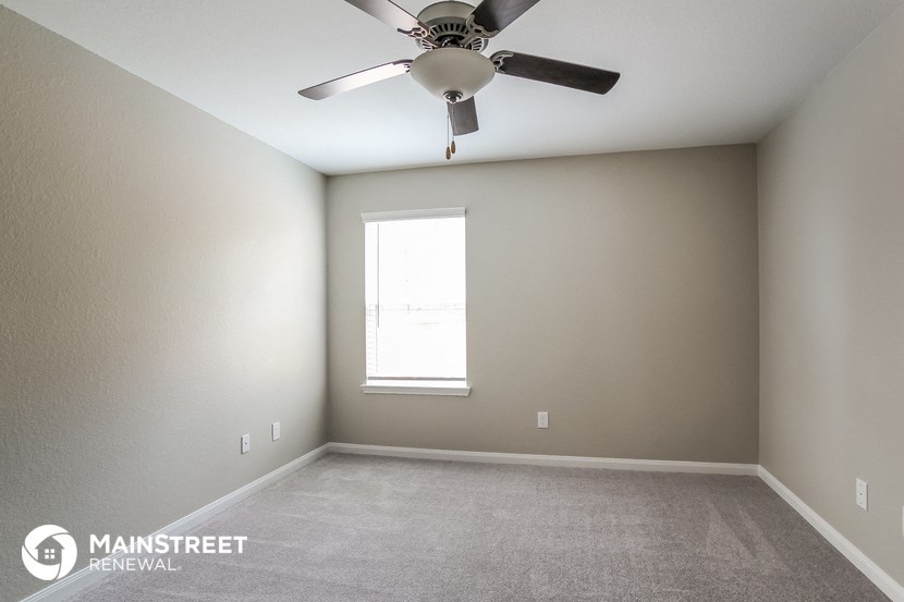 an empty room with a ceiling fan and a window