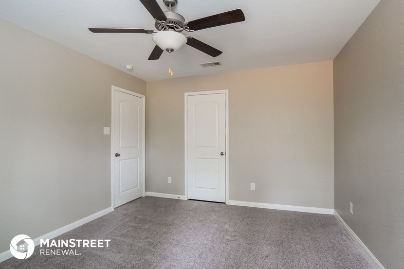 the master bedroom has a carpeted floor and a ceiling fan