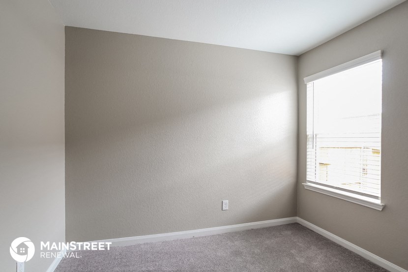 a bedroom with a large window and a carpeted floor