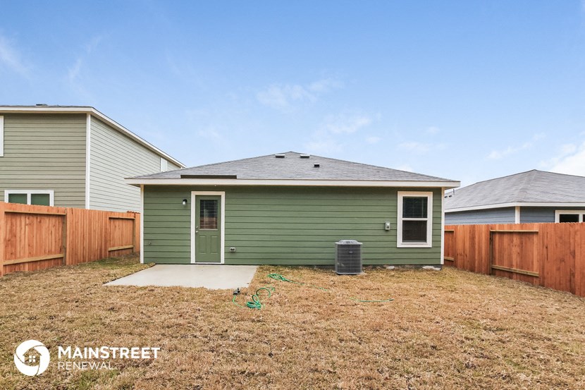 a green house with a yard and a wooden fence