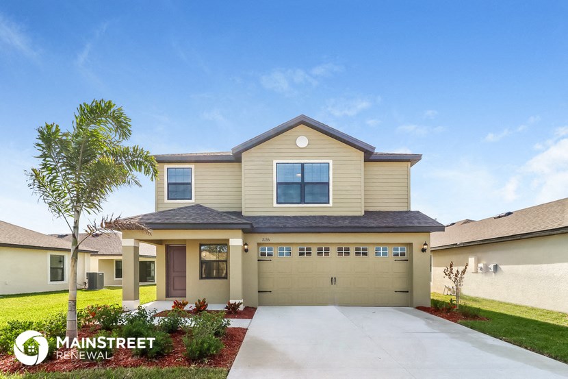 a beige house with a garage and a palm tree