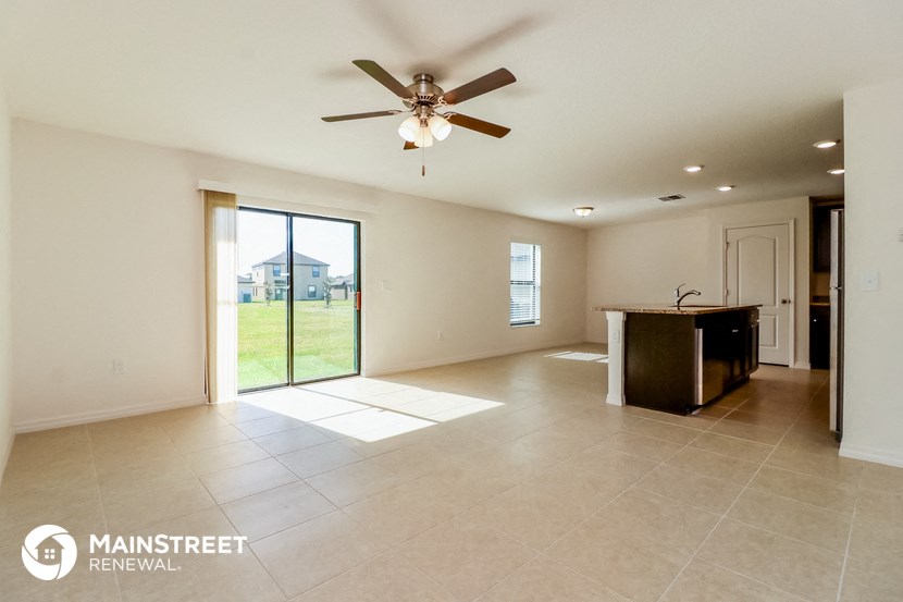 an empty living room with a ceiling fan and sliding glass doors