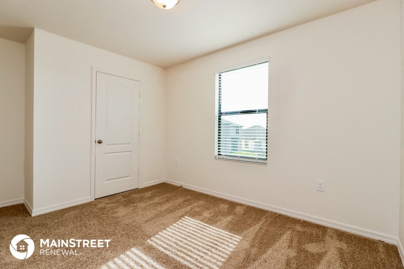 the living room of an apartment with carpet and a window