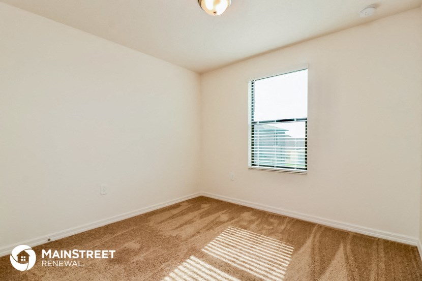 a spacious living room with a window and a carpeted floor