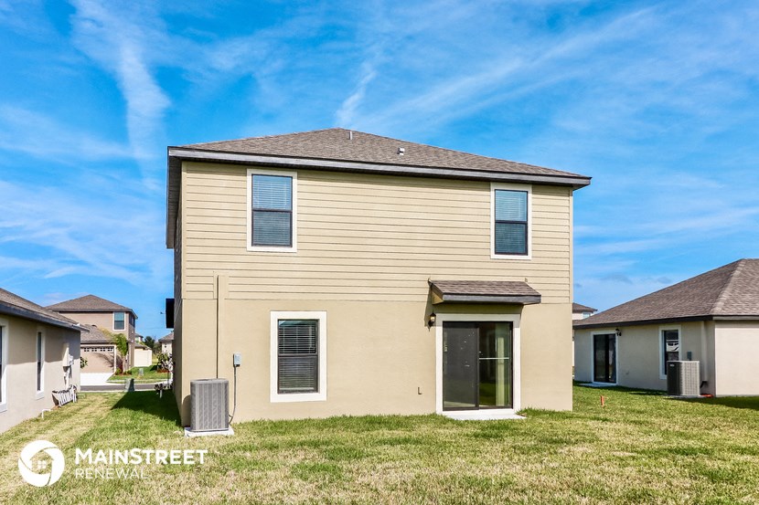 a beige house with a grassy yard and a blue sky