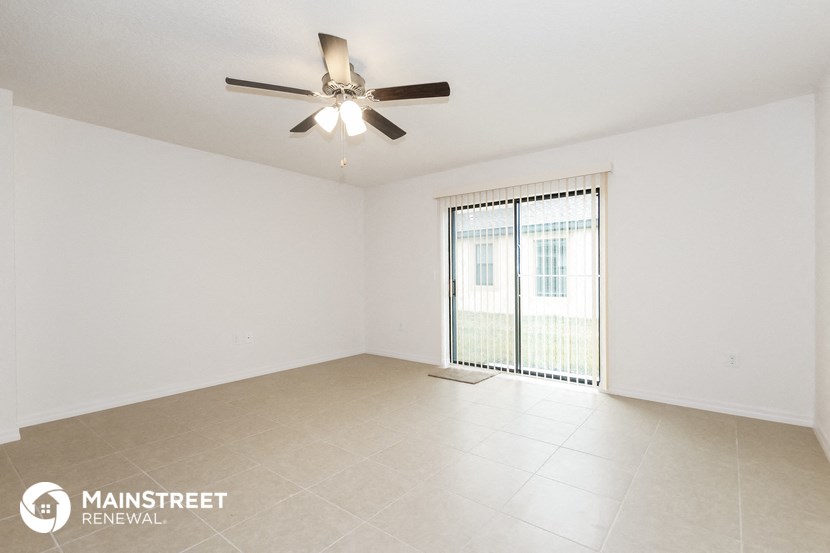 a living room with a ceiling fan and a large window