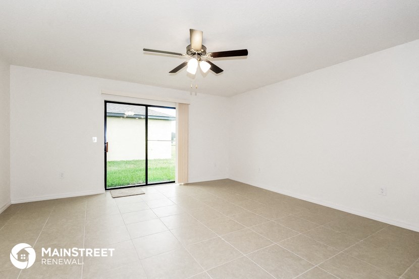 the spacious living room with ceiling fan and tile flooring