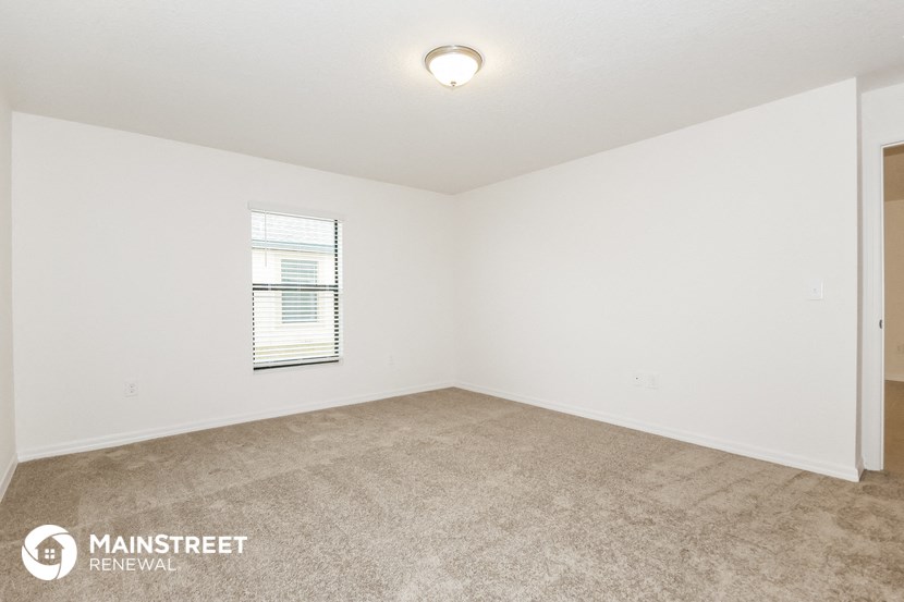 the spacious living room with carpeting and a window