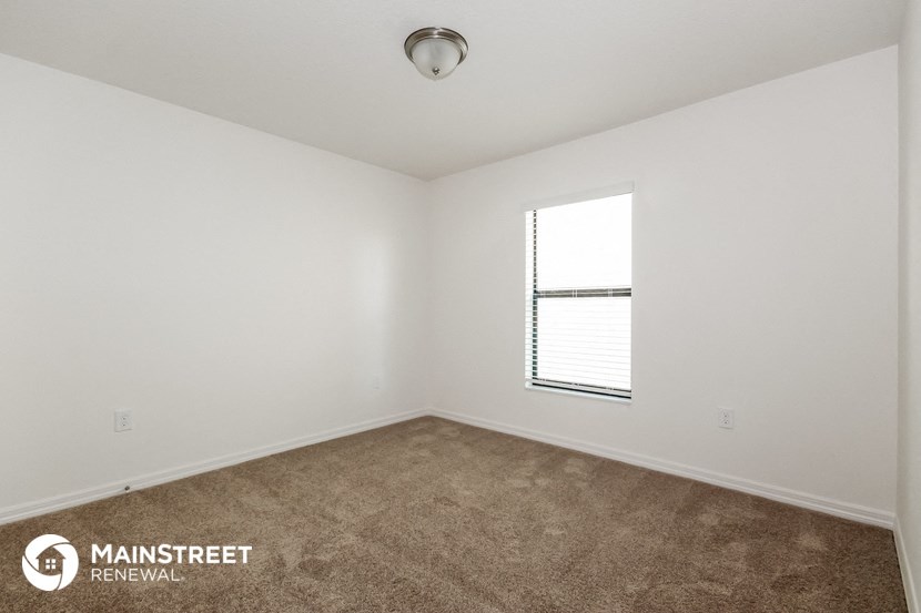 the spacious living room with carpeting and a window
