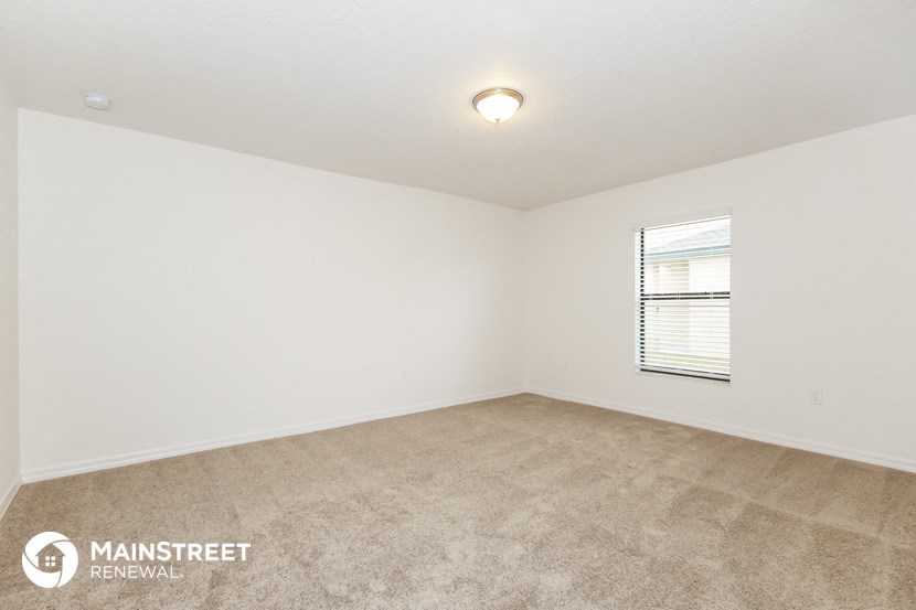 the spacious living room with carpeting and a window