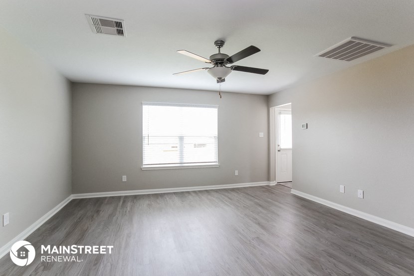 an empty living room with a ceiling fan and a window