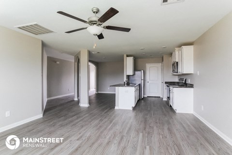 an open kitchen and living room with white cabinets and a ceiling fan