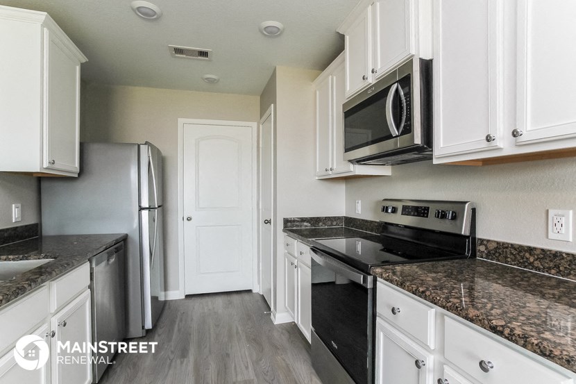a kitchen with white cabinets and granite counter tops and black appliances
